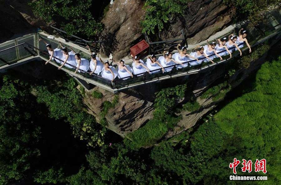 Dancers perform ballet on cliff, glass walkway