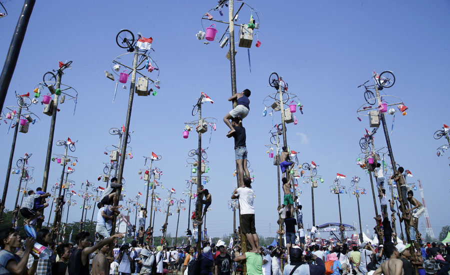 Men in Indonesia climb greased poles to win prizes